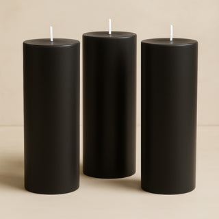 Black pillar candles in varying heights on a neutral background.