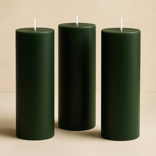Green pillar candles in various heights on a neutral background.