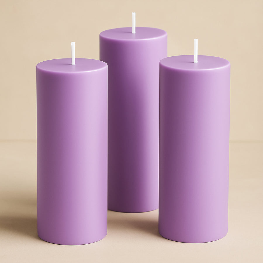 Three purple pillar candles of varying heights against a neutral background.