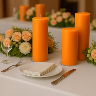 Orange candles with floral arrangement on a dining table setting.