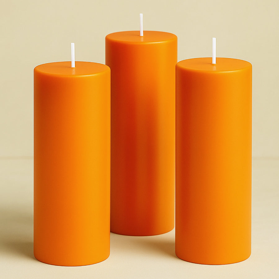 Three vibrant orange pillar candles in varying heights.