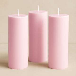 Three pink pillar candles in varying heights on a neutral background.