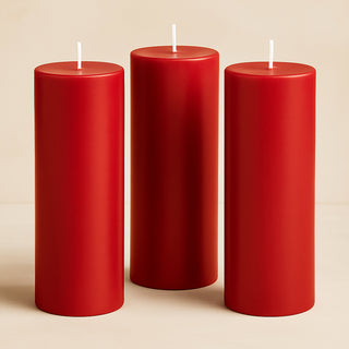 Three red pillar candles in varying heights on a neutral background.