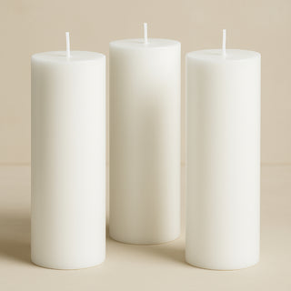 Three white pillar candles in varying heights on a soft beige background.
