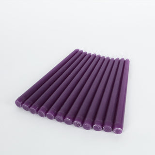 Purple taper candles arranged in a row on a plain background.