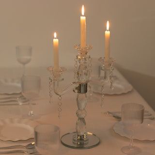 Elegant crystal candle holder with three lit candles on a dining table.