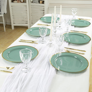 Elegant green dinner plates set on a table with glassware and candles.