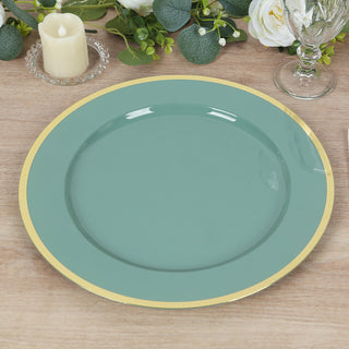 Teal dinner plate with gold rim on wooden table surrounded by greenery.