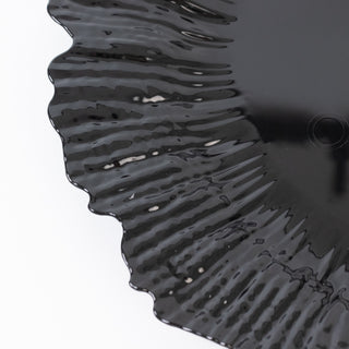 Black decorative plate with wavy edges on a plain background