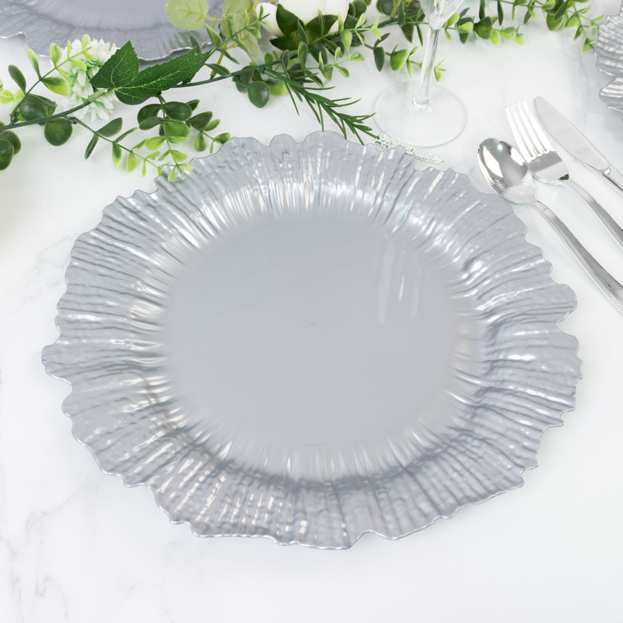 Silver ruffled charger plate on a marble table with greenery