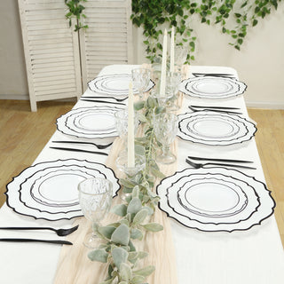 Elegant black and white dinnerware set arranged on a table with greenery accents.