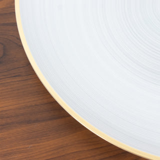 Elegant white plate with a gold rim on a wooden surface.