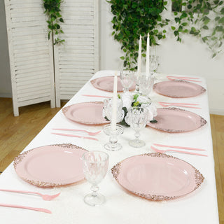 Elegant pink plates set on a dining table with glassware and candles.