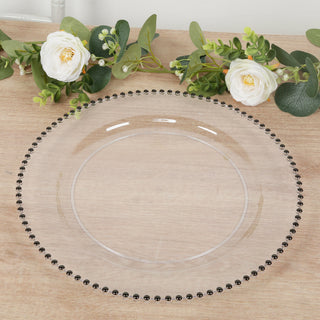 Clear glass plate with decorative black beading, surrounded by greenery and flowers.