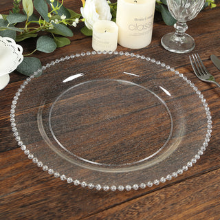 Elegant clear glass charger plate with beaded rim on wooden table.