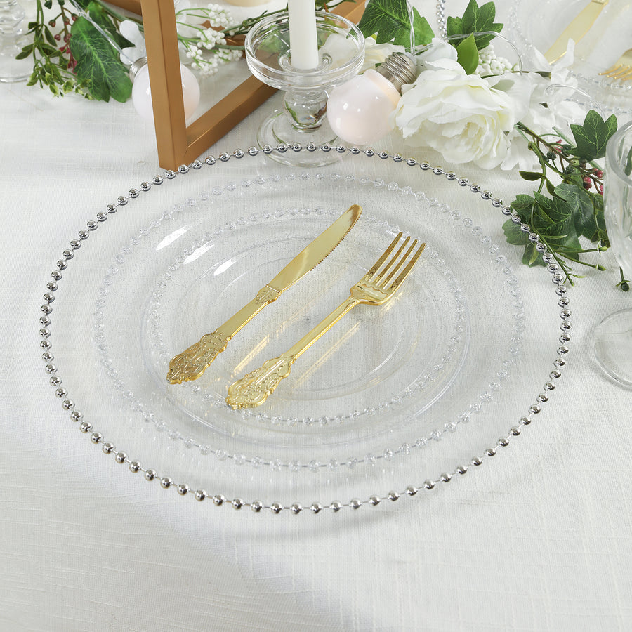 Elegant clear plate with ornate gold knife and fork on a decorated table.
