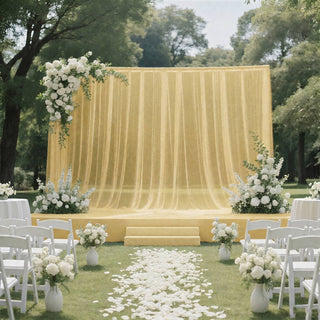 Elegant outdoor wedding ceremony with yellow draped stage and white floral decor