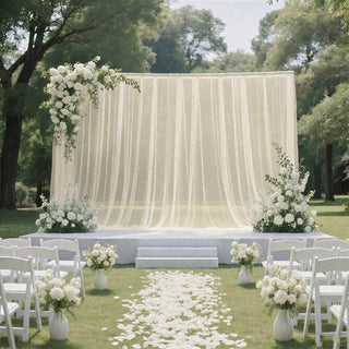Elegant outdoor wedding ceremony setup with white flowers and draped backdrop