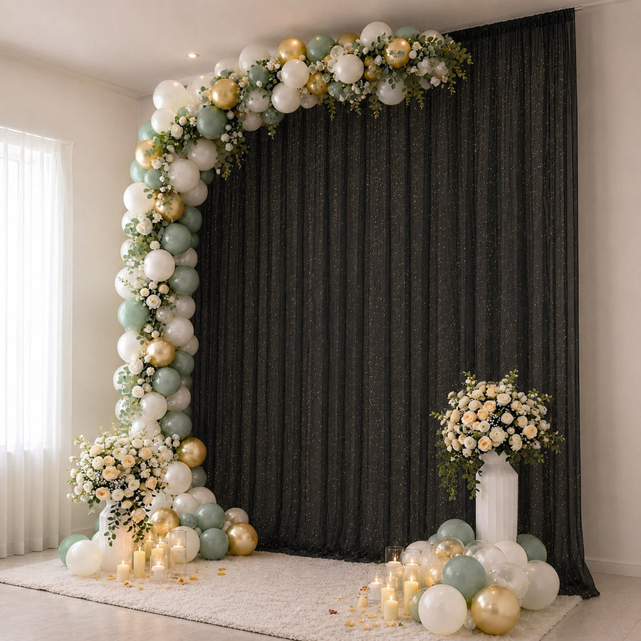 Elegant balloon arch with floral arrangements and candles on a black backdrop.
