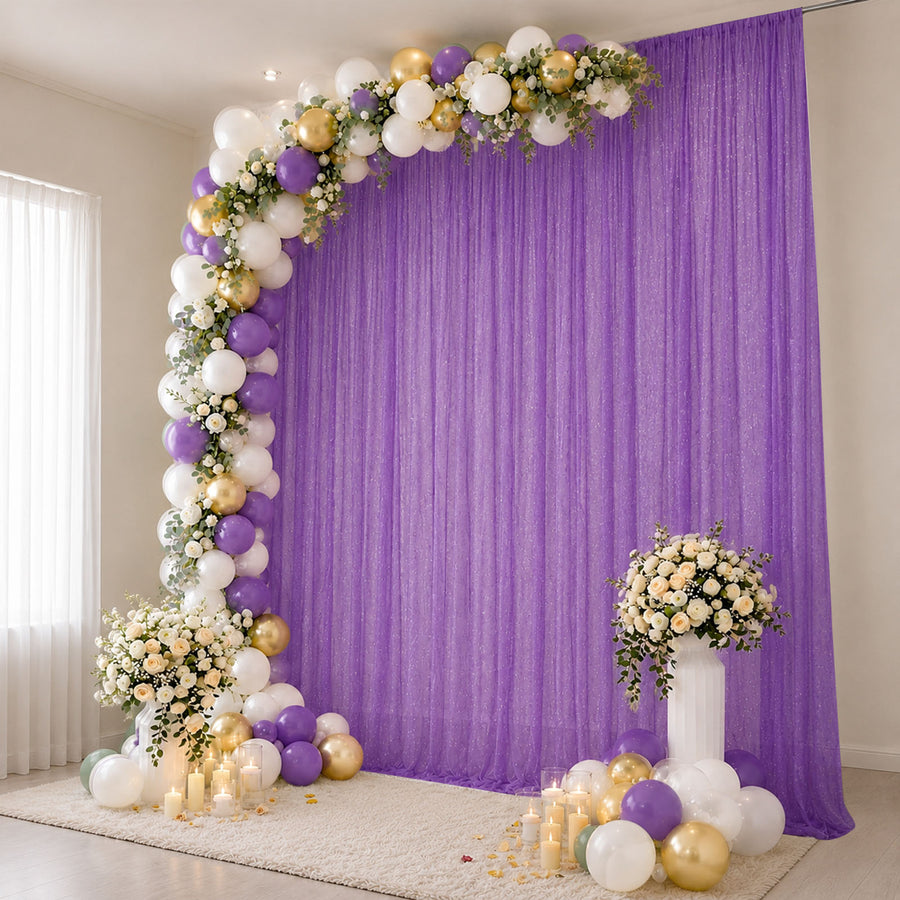 Purple and gold balloon arch with floral backdrop and candles for party decor