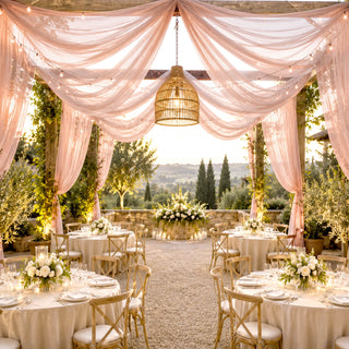 Elegant outdoor wedding reception with pink drapes, string lights, and scenic views