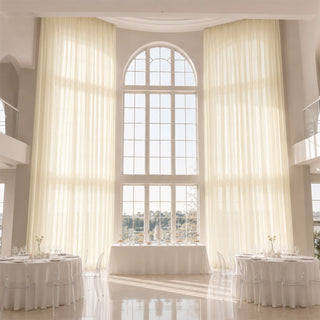 Elegant white wedding reception hall with tall arched window and sheer drapes