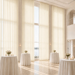 Elegant white wedding reception venue with tall curtains and floral table decor