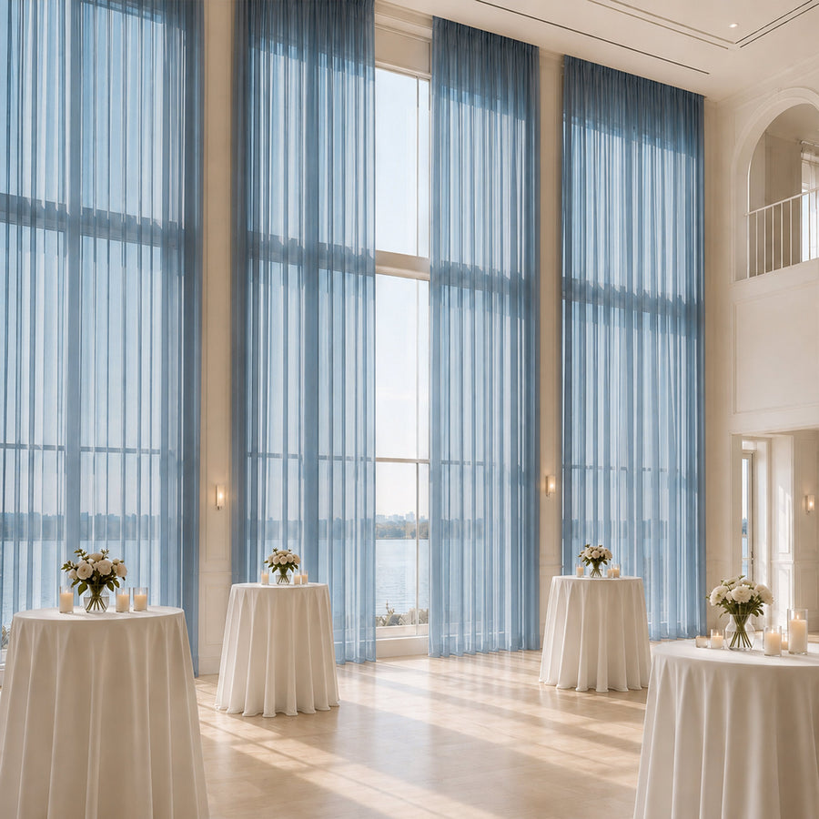 Elegant waterfront event hall with tall blue drapes and cocktail tables