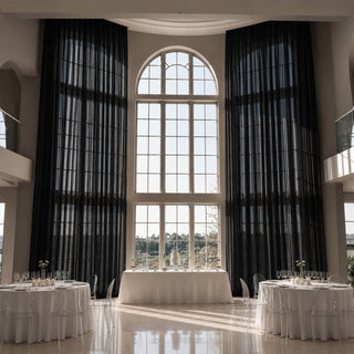 Elegant wedding reception venue with tall arched window and black drapes