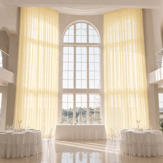 Elegant sunlit wedding reception hall with tall arched windows and white tables