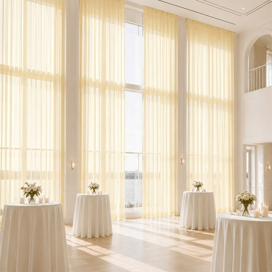 Elegant sunlit event venue with sheer curtains and cocktail tables by the water