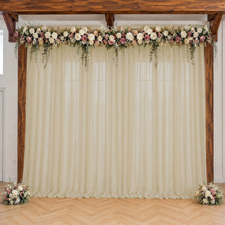 Elegant wedding arch with floral garland and ivory drapes indoors