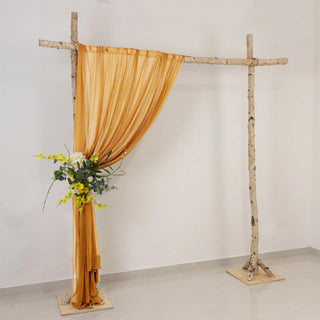 Rustic birch wedding arch with gold drape and floral arrangement