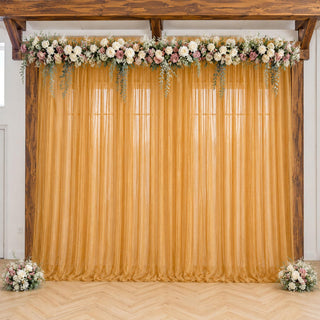 Gold wedding backdrop with floral garland, sheer curtain, and wooden frame