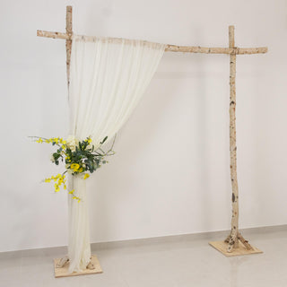 Rustic birch wedding arch with white drape and yellow floral arrangement