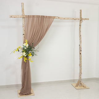 Rustic wedding backdrop with draped fabric and floral arrangement.