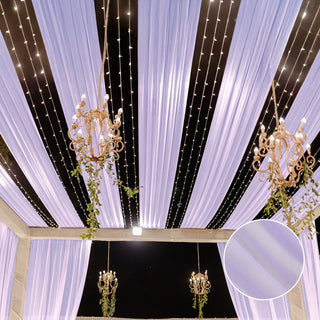 Elegant purple drapery and chandeliers with fairy lights in a decorated venue.