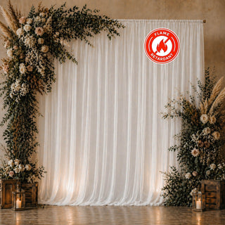 Elegant wedding backdrop with white drapery, floral arch, and lanterns