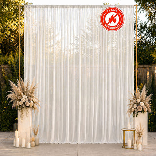 Elegant white sheer draped wedding backdrop with floral décor and candles