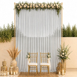 Elegant wedding ceremony backdrop with white drapes, roses, gold chairs, and candles