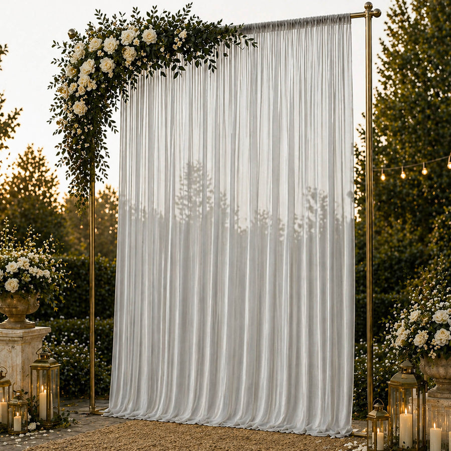 Elegant wedding backdrop with white drapes, gold frame, roses, and lanterns