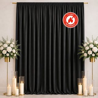 Black flame retardant curtain backdrop with white floral candles and gold stands