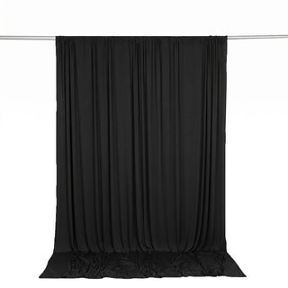 Black draped curtain backdrop hanging on a silver rod, studio background