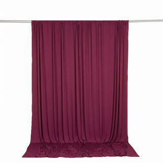 Burgundy velvet curtain draped on a rod against a white background