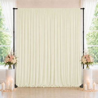 Elegant wedding backdrop with cream drape, floral arrangements, and candles