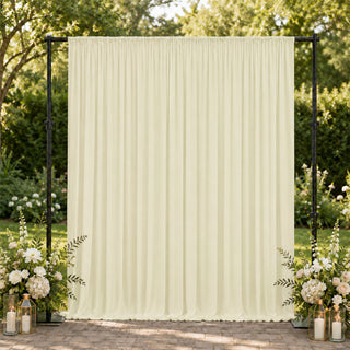 Cream draped wedding backdrop with floral arrangements and lanterns outdoors
