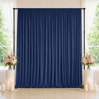 Navy blue draped wedding backdrop with floral arrangements and candles