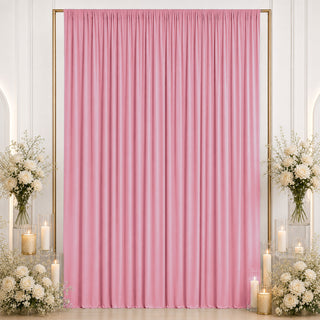 Pink draped backdrop with white floral arrangements and candles for event decor