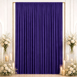 Purple draped backdrop with white floral arrangements and candle decor