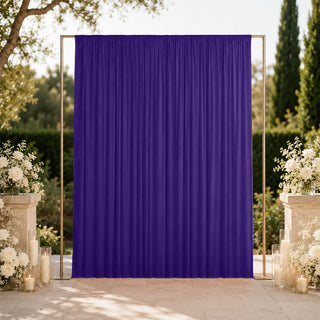 Purple draped wedding backdrop with floral candle decor outdoors